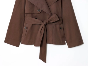 Close-up of a short brown trench coat featuring resin buttons and a tied waist belt