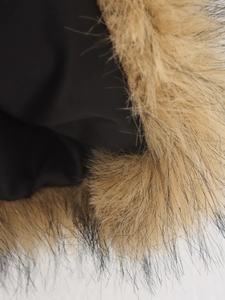 Gros plan du col en fausse fourrure pelucheuse et du tissu noir de cette veste femme