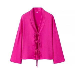Detail of rose pink long sleeve top featuring triple bow-tie front closures and crinkled fabric