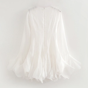 Close-up of white long sleeve mini dress with layered ruffle hem and textured fabric