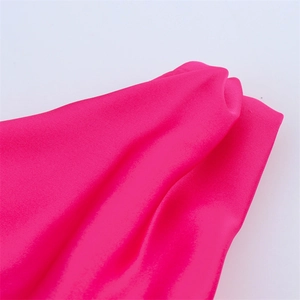 Détail macro de la texture du tissu rose fuchsia et des coutures de la robe asymétrique
