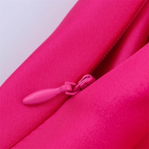 Détail d'une fermeture éclair invisible sur une robe en satin rose vif et soyeux