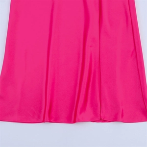Détail de robe en satin fuchsia montrant la fente latérale et la texture soyeuse lisse
