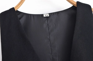 Détail du décolleté et de l'étiquette de taille XS sur une robe noire sans manches