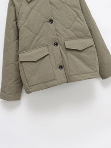 Detail of olive green quilted jacket showing diamond stitching and large flap pockets
