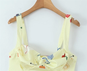 Detail of light yellow camisole top featuring thin straps and pleated chest design