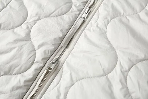 Détail du zip métallique double et du matelassage ondulé sur la veste légère rembourrée