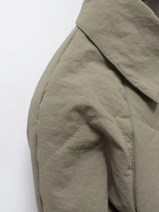 Macro shot of wave-quilted olive green jacket fabric showing detailed stitching and nylon texture