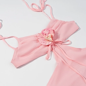 Detail eines rosa Halterkleides mit 3D-Blumendekor und plissierter Textur im Stoff