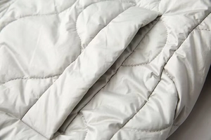 Détail du matelassage oignon et poche en biais sur la veste rembourrée gris clair