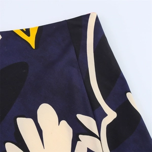 Detail of high-waisted skirt featuring navy blue fabric with yellow abstract floral prints