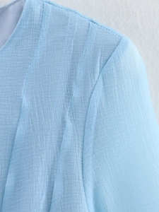 Detail shot of light blue crinkle fabric texture on round neck dress shoulder seam