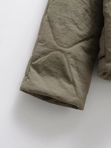 Detailed macro shot of olive green quilted jacket cuff with wavy stitching pattern