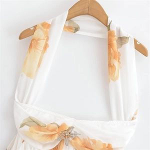 Détail de la robe licou blanche à fleurs orange avec décoration d'étoile de mer en strass