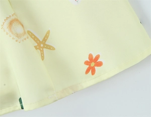 Detailed close-up of yellow dress hem with sun and starfish prints and neat stitching