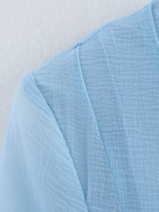 Detail of light blue chiffon dress shoulder seam with smooth stitching and textured fabric
