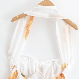 Détail de la robe dos nu à fleurs orange sur tissu en mousseline de soie blanche