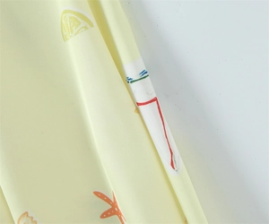 Detail of summer dress fabric featuring yellow lemon and orange starfish prints