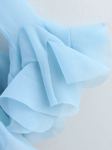 Macro shot of light blue sheer chiffon fabric with layered ruffles and textured finish