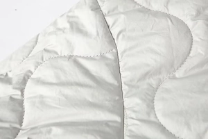 Gros plan sur le tissu matelassé gris clair d'une veste montrant coutures et texture