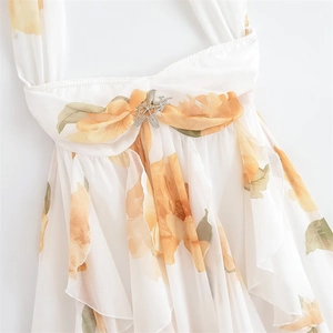 Détail de robe dos nu à fleurs avec volants superposés et boucle étoile de mer en strass