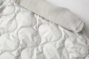 Détail macro de la veste matelassée ondulée avec col en tricot côtelé et fermeture éclair