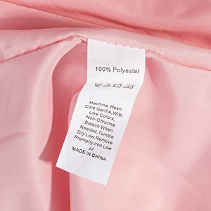 Detailansicht des Pflegeetiketts mit 100 % Polyester und Waschanleitungen für Kleidung