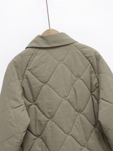 Detail of onion-quilted khaki jacket with raglan sleeves and turn-down collar on hanger