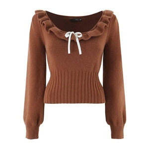 Detail of ruffle neckline with white ribbon bow on brown long sleeve knit sweater