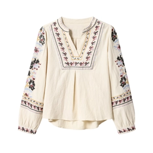Dettaglio del ricamo etnico multicolore sullo scollo a V della camicia in cotone bianco