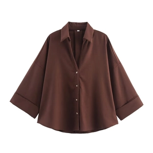 Close-up of deep brown loose-fit shirt featuring V-neckline and metallic buttons