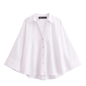 Detailed view of the white long-sleeve loose shirt with elegant gold metal buttons