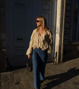 Close-up of elegant beige V-neck blouse with layered ruffles and long lantern sleeves