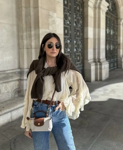 Close-up of elegant ruffled V-neck blouse paired with a stylish mini crossbody bag