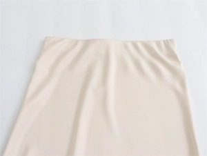 Close-up of a seamless high-waist band on a cream satin long skirt with smooth texture