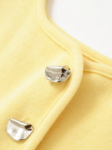Dettaglio del tessuto a maglia giallo con bottoni metallici argentati lucidi