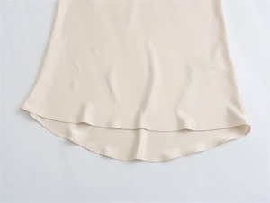 Macro view of cream silk satin skirt hem showing refined stitching and fluid drape