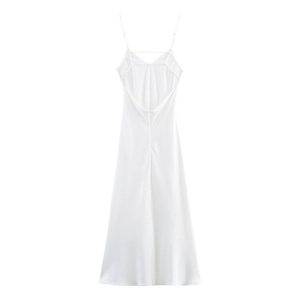 Detailed view of white satin slip dress featuring backless cross straps and v-neckline