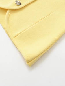 Dettaglio di un top in maglia giallo chiaro con cuciture rifinite e bottone in argento