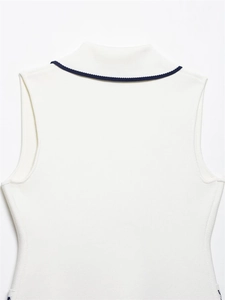 Close-up detail of white sleeveless knit top featuring elegant navy blue trim on neckline