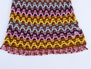 Détail du motif en tricot chevron coloré et des glands à franges sur une robe bohème