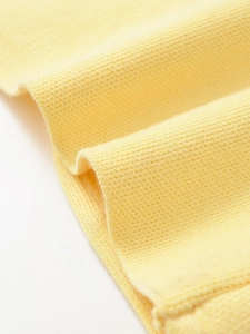 Dettaglio ravvicinato del tessuto a maglia giallo con cuciture fini e trama morbida del materiale