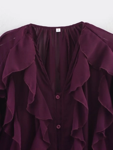 Macro view of burgundy chiffon V-neck shirt with ruffle layering and buttons