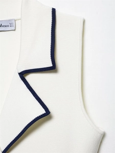 Detail of white knit vest collar with navy contrast trim and woven size label