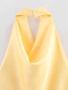 Detail eines gelben Satin-Neckholder-Tops mit drapiertem Ausschnitt und Knopfkragen