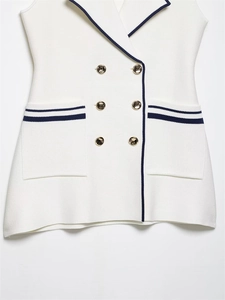 Close-up of white sleeveless knit vest with navy trim and golden double-breasted buttons