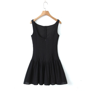 Detail of a chic black backless mini dress with hidden zipper and pleated A-line skirt hem