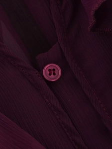 Macro shot of dark purple chiffon fabric with detailed resin button and vertical texture