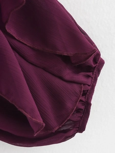 Detail view of burgundy chiffon ruffles with delicate stitching on a V-neck shirt