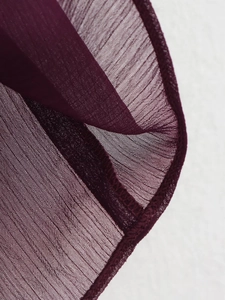 Macro detail of wine red chiffon fabric texture with precise overlock stitching edge